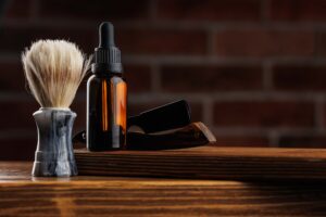 Beard grooming supplies on a wooden counter with a brick background.