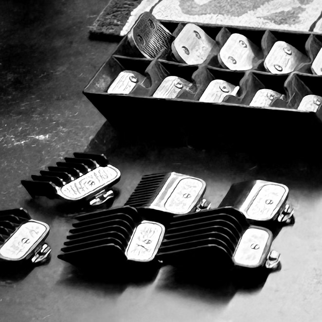 A black and white styled image of trimmer attachments. The attachments are placed on the counter of a barber's station.